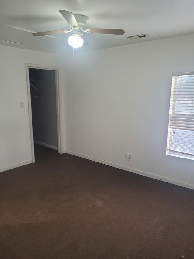 spare room with dark colored carpet and ceiling fan