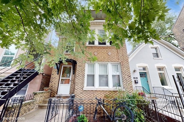 view of front of home featuring a fenced front yard, brick siding, and stairs