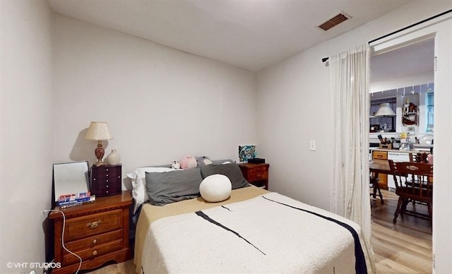 bedroom featuring wood finished floors and visible vents