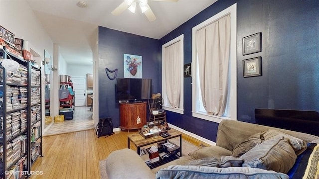 living area featuring light wood-type flooring, ceiling fan, and baseboards