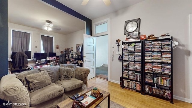 living room with a ceiling fan, light wood-style floors, and baseboards