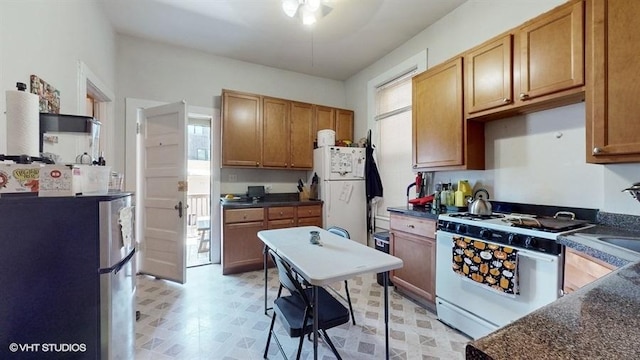 kitchen featuring white appliances, dark countertops, and brown cabinets