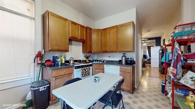 kitchen with dark countertops, white appliances, and brown cabinets