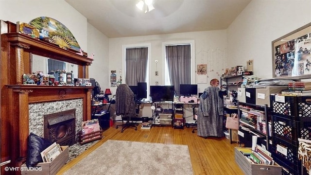 office area with a fireplace with flush hearth, ceiling fan, and light wood finished floors