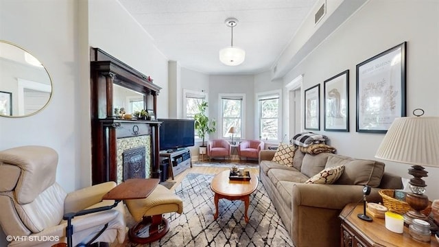 living room with a fireplace, visible vents, and wood finished floors