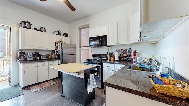 kitchen featuring a center island, stainless steel appliances, a ceiling fan, white cabinetry, and a sink