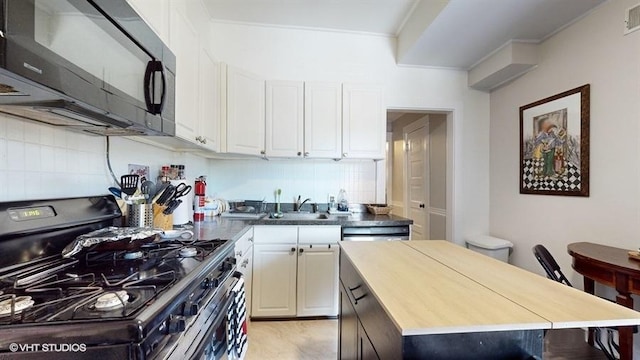 kitchen with black microwave, a sink, white cabinets, decorative backsplash, and range with gas cooktop