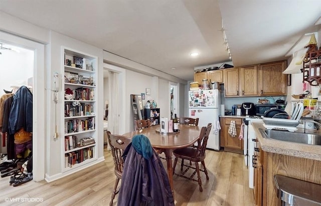 kitchen featuring light wood finished floors, light countertops, a sink, and freestanding refrigerator