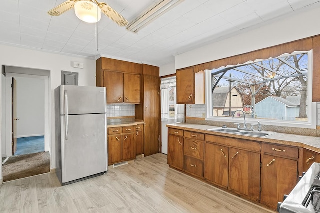 kitchen featuring stainless steel refrigerator, light hardwood / wood-style floors, sink, and decorative backsplash