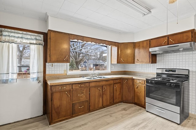 kitchen with sink, backsplash, gas range oven, and light hardwood / wood-style flooring