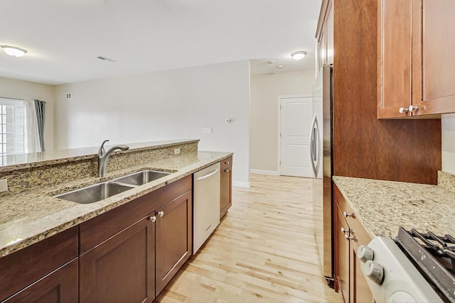 kitchen featuring light stone counters, sink, light hardwood / wood-style flooring, and appliances with stainless steel finishes