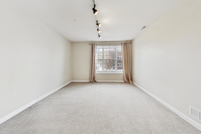 spare room featuring light colored carpet and rail lighting