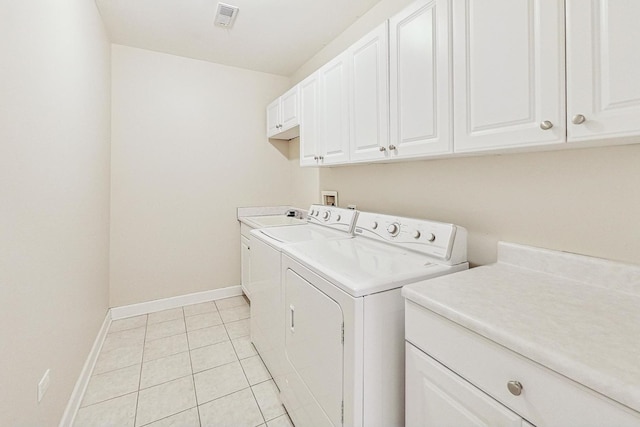 laundry area featuring light tile patterned flooring, cabinets, and washing machine and dryer