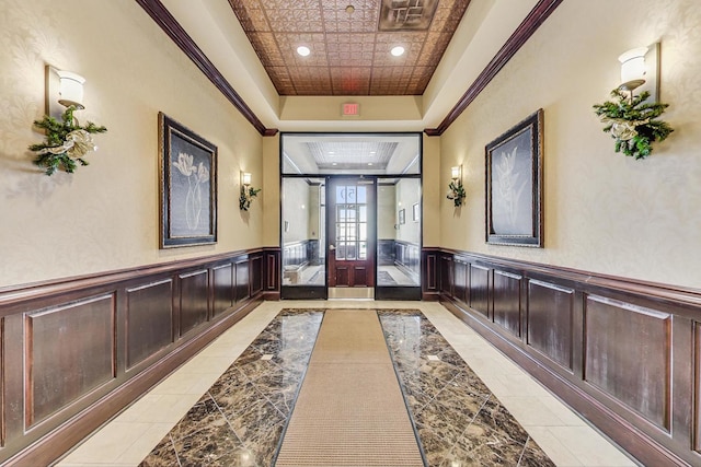 corridor with ornamental molding and a tray ceiling