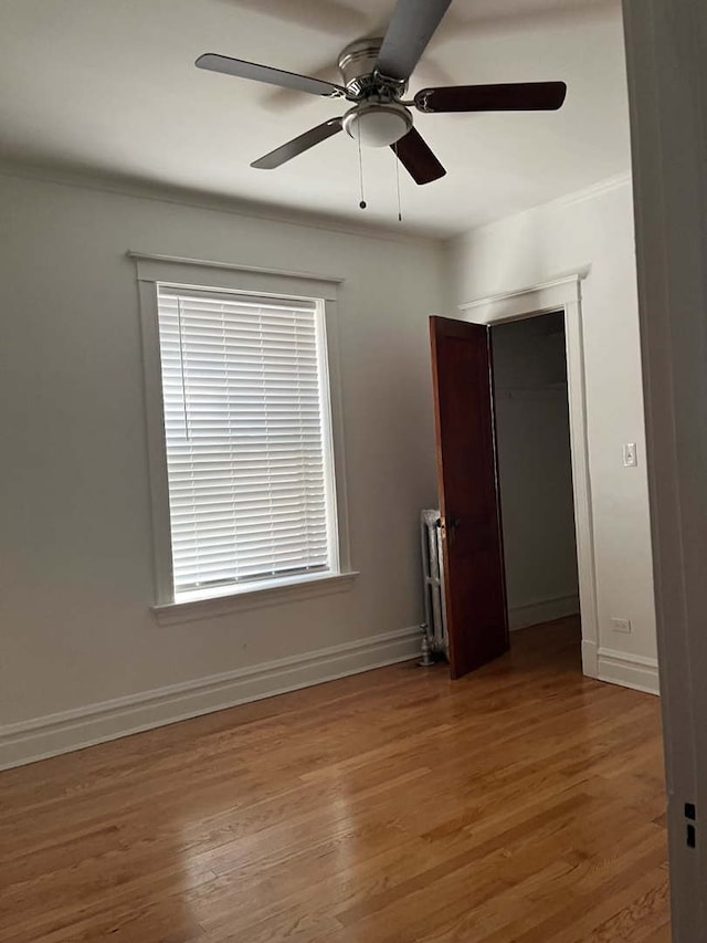 unfurnished room with hardwood / wood-style flooring, radiator heating unit, and ceiling fan