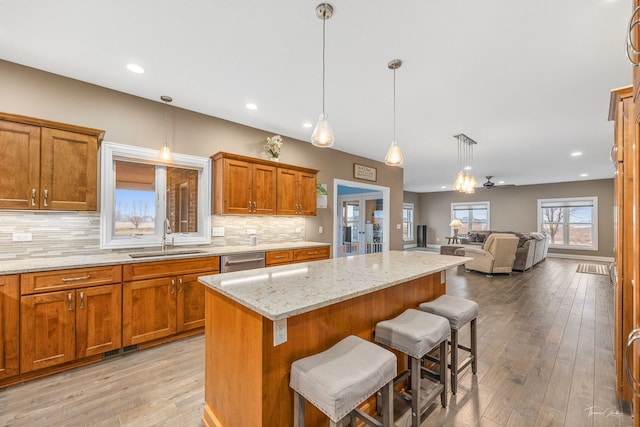 kitchen with sink, a breakfast bar, dishwasher, light stone countertops, and a kitchen island