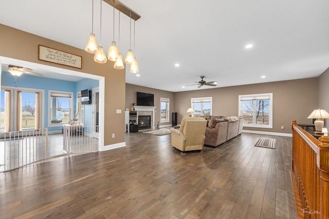 living room featuring ceiling fan with notable chandelier and dark wood-type flooring