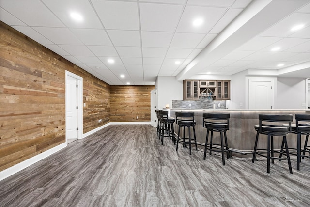 bar featuring hardwood / wood-style flooring, decorative backsplash, and wood walls