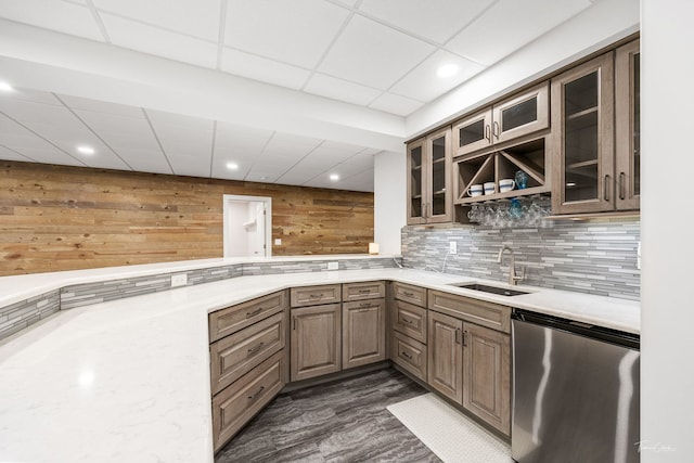 kitchen with sink, dishwasher, backsplash, dark hardwood / wood-style floors, and wood walls