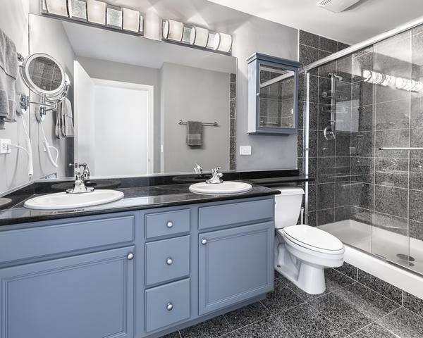 bathroom featuring toilet, a stall shower, granite finish floor, and a sink