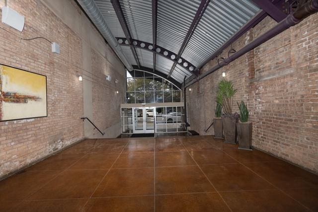 interior space featuring brick wall, a towering ceiling, and tile patterned floors