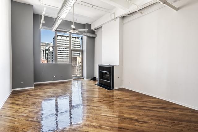 interior space featuring ceiling fan, wood finished floors, a fireplace with flush hearth, and baseboards