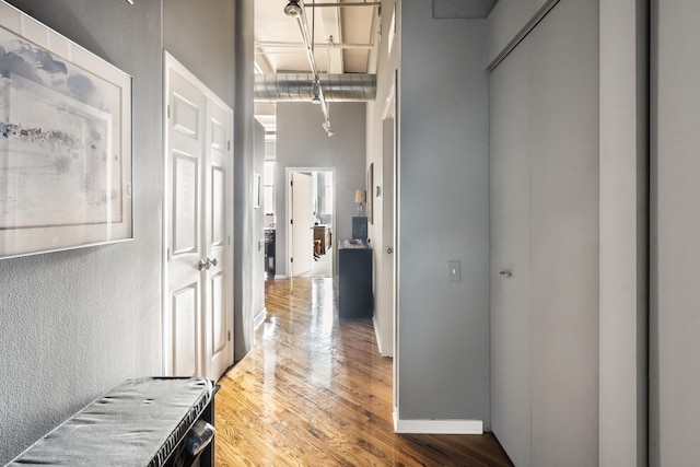 hallway featuring a high ceiling, wood finished floors, and baseboards