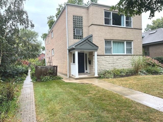 view of front of property with stone siding, a front lawn, and brick siding