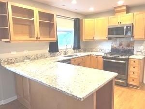 kitchen featuring light stone counters, a peninsula, stainless steel appliances, light wood-style floors, and open shelves