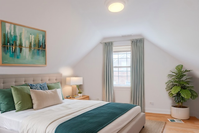 bedroom with wood-type flooring and vaulted ceiling