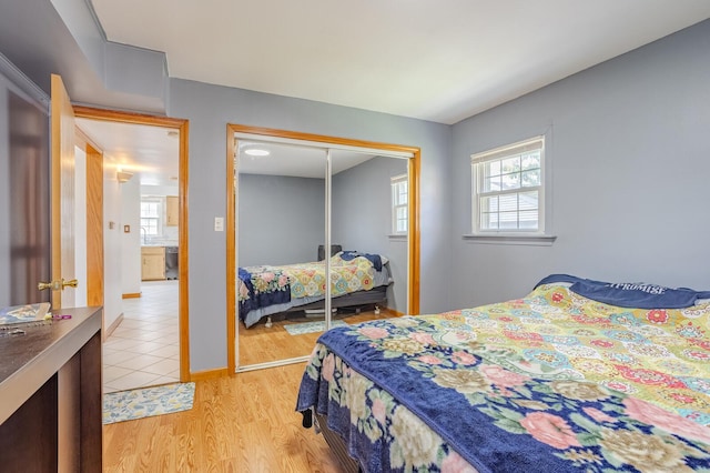 bedroom with multiple windows, light hardwood / wood-style flooring, and a closet