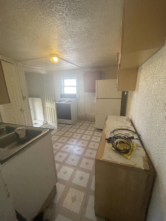 kitchen with sink, a textured ceiling, and white fridge