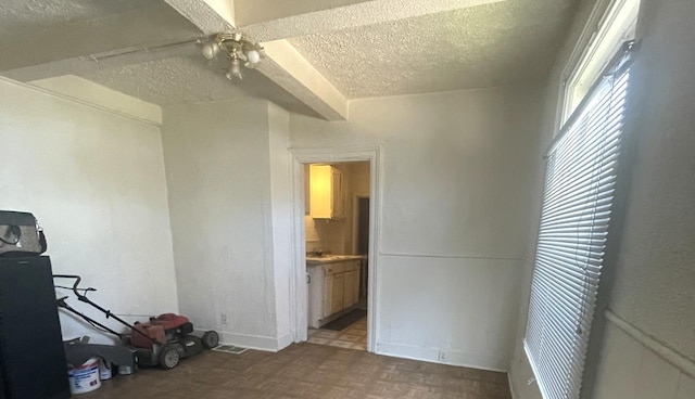 unfurnished bedroom featuring ceiling fan, parquet flooring, ensuite bathroom, and a textured ceiling