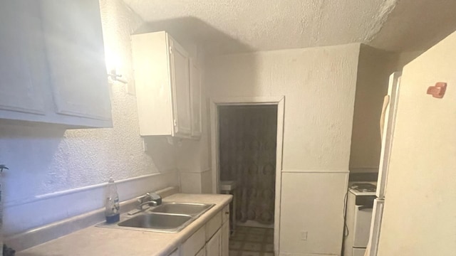 kitchen with sink, white cabinets, and a textured ceiling