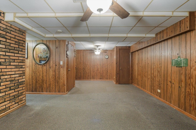 basement featuring light colored carpet, ceiling fan, and wood walls