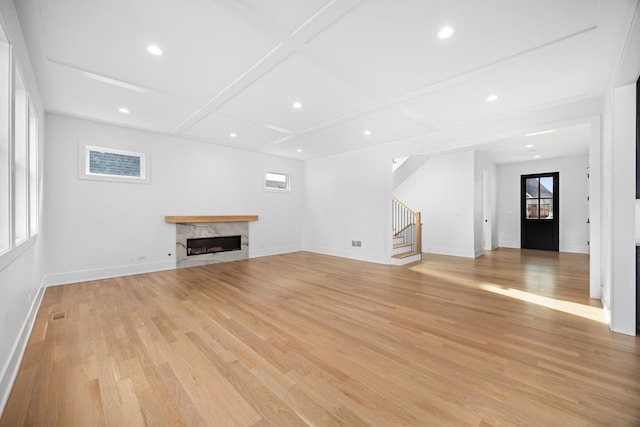 unfurnished living room with light hardwood / wood-style flooring, a high end fireplace, and coffered ceiling