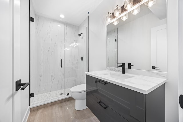 bathroom with a shower with door, vanity, and toilet