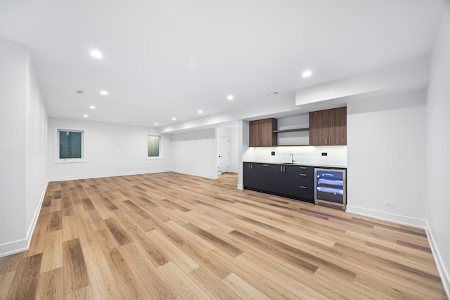 unfurnished living room featuring wine cooler, light hardwood / wood-style flooring, and wet bar