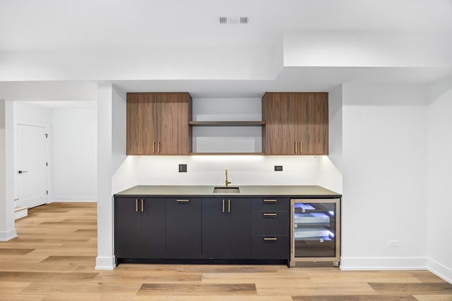 kitchen with dark brown cabinetry, sink, wine cooler, and light hardwood / wood-style floors