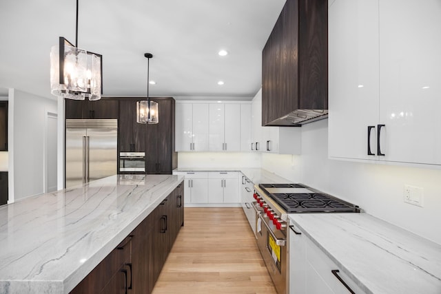 kitchen with premium range hood, white cabinets, premium appliances, hanging light fixtures, and dark brown cabinets