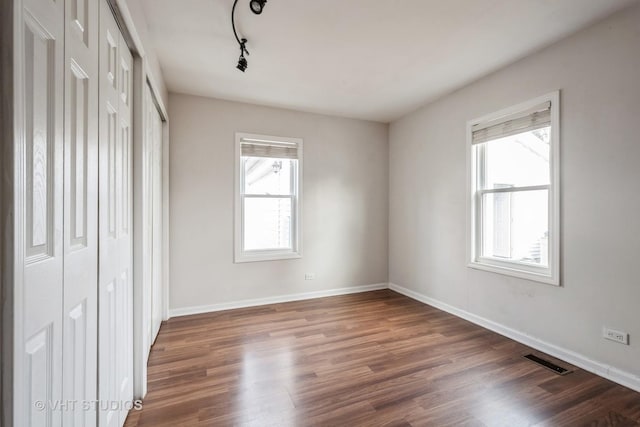 unfurnished bedroom featuring dark wood-type flooring and track lighting