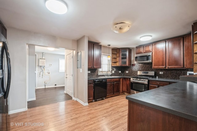 kitchen with sink, tasteful backsplash, decorative light fixtures, light wood-type flooring, and appliances with stainless steel finishes