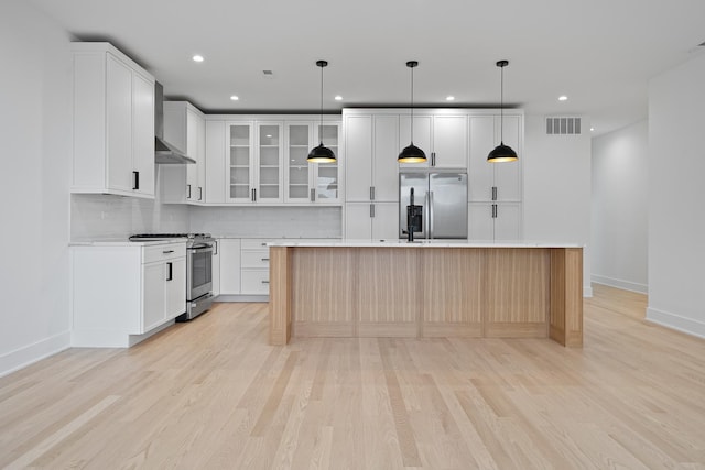 kitchen featuring appliances with stainless steel finishes, pendant lighting, tasteful backsplash, an island with sink, and white cabinets