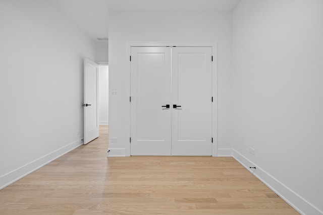 unfurnished bedroom with light wood-type flooring and a closet