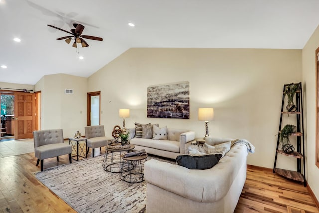 living room with lofted ceiling, light wood-style flooring, visible vents, and a ceiling fan