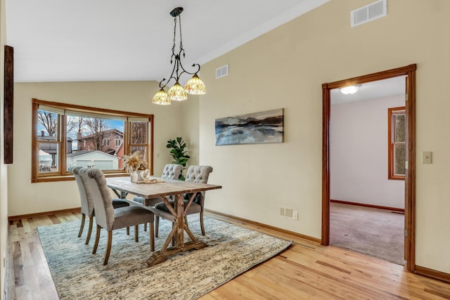 dining area featuring light wood-style flooring, visible vents, vaulted ceiling, and baseboards