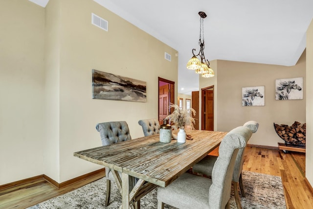 dining room featuring lofted ceiling, light wood finished floors, and visible vents