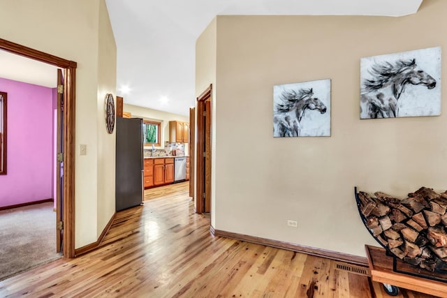 hallway with baseboards, visible vents, and light wood-style floors