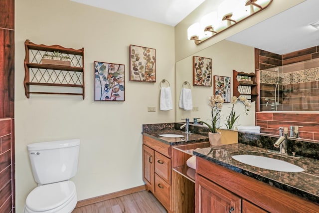 full bathroom with double vanity, a sink, toilet, and wood finished floors