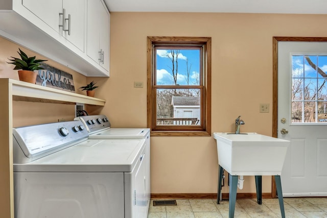 laundry area with cabinet space, washing machine and dryer, visible vents, and baseboards